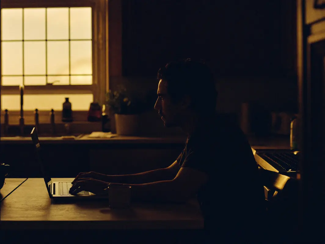 Man finishing a quick online form at his kitchen table in evening light